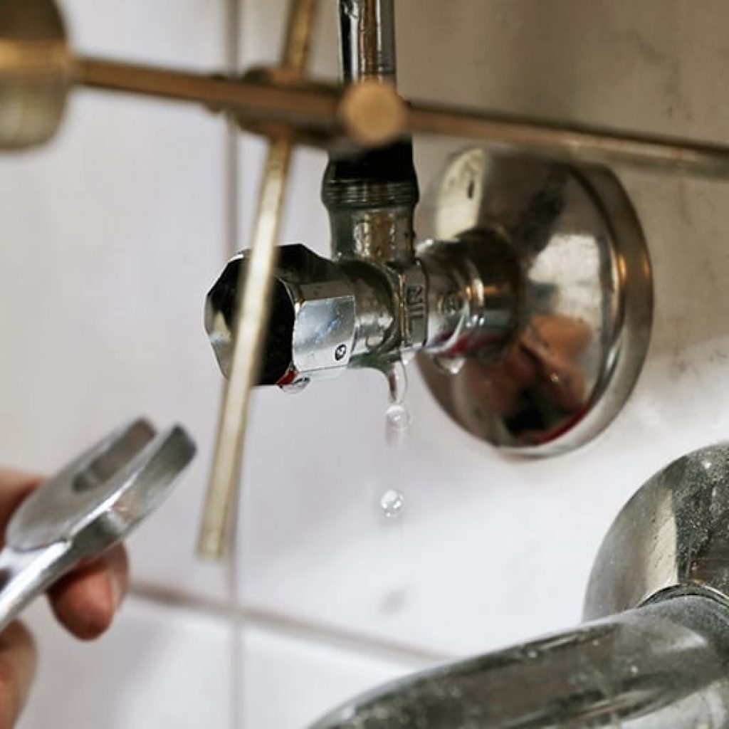 plumber fixing a leak under a bathroom sink